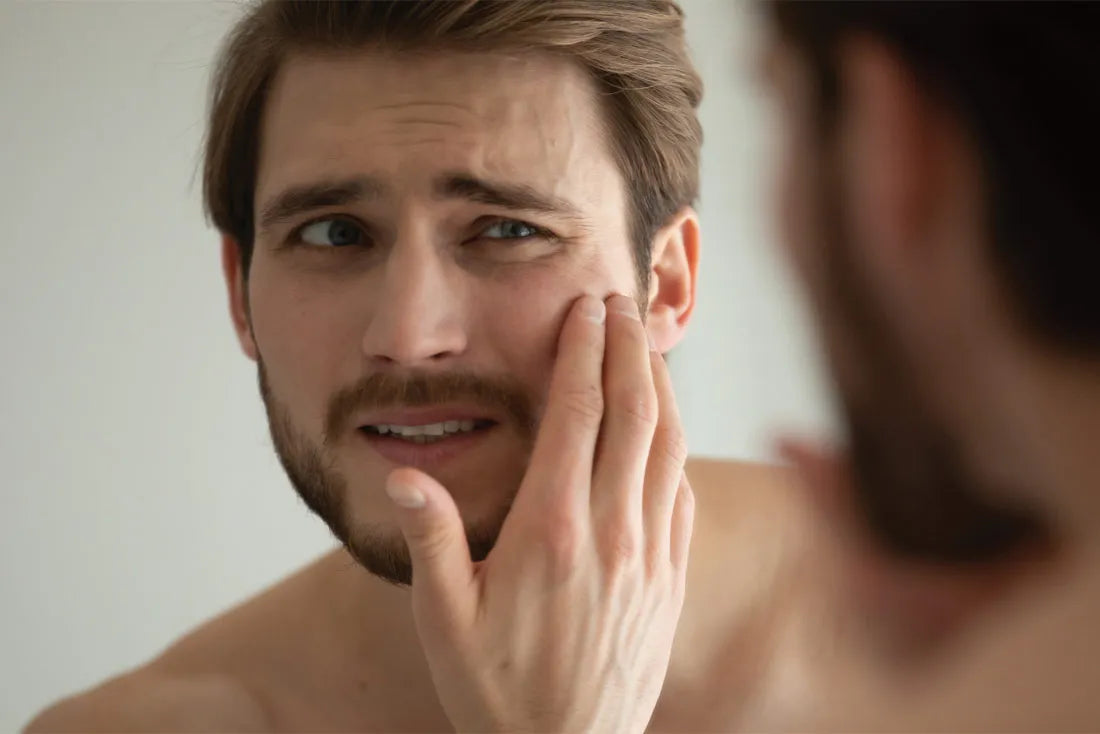 man with oily skin looking in mirror